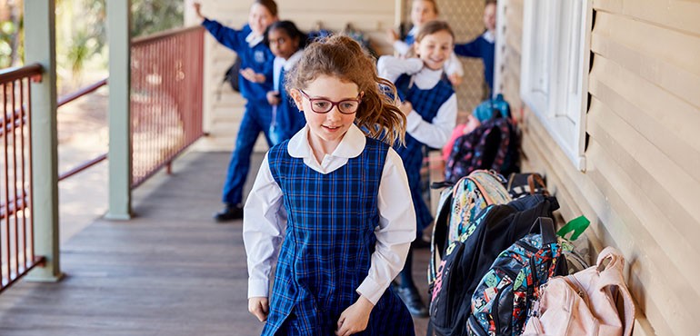 SWS770-Young_female_student_in_glasses_smiling Student collecting their bags outside their classroom.
